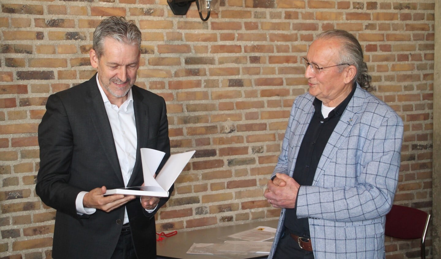 Schrijver Gerard van Loenen (rechts) overhandigt het eerste exemplaar aan burgemeester Hans van der Pas