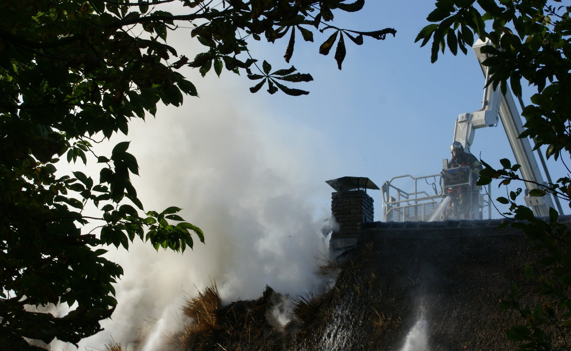 De brandweer blust het smeulende rieten dak van de historische boerderij aan de Boomstraat in Gemonde. (Foto: Marc Cleutjens).