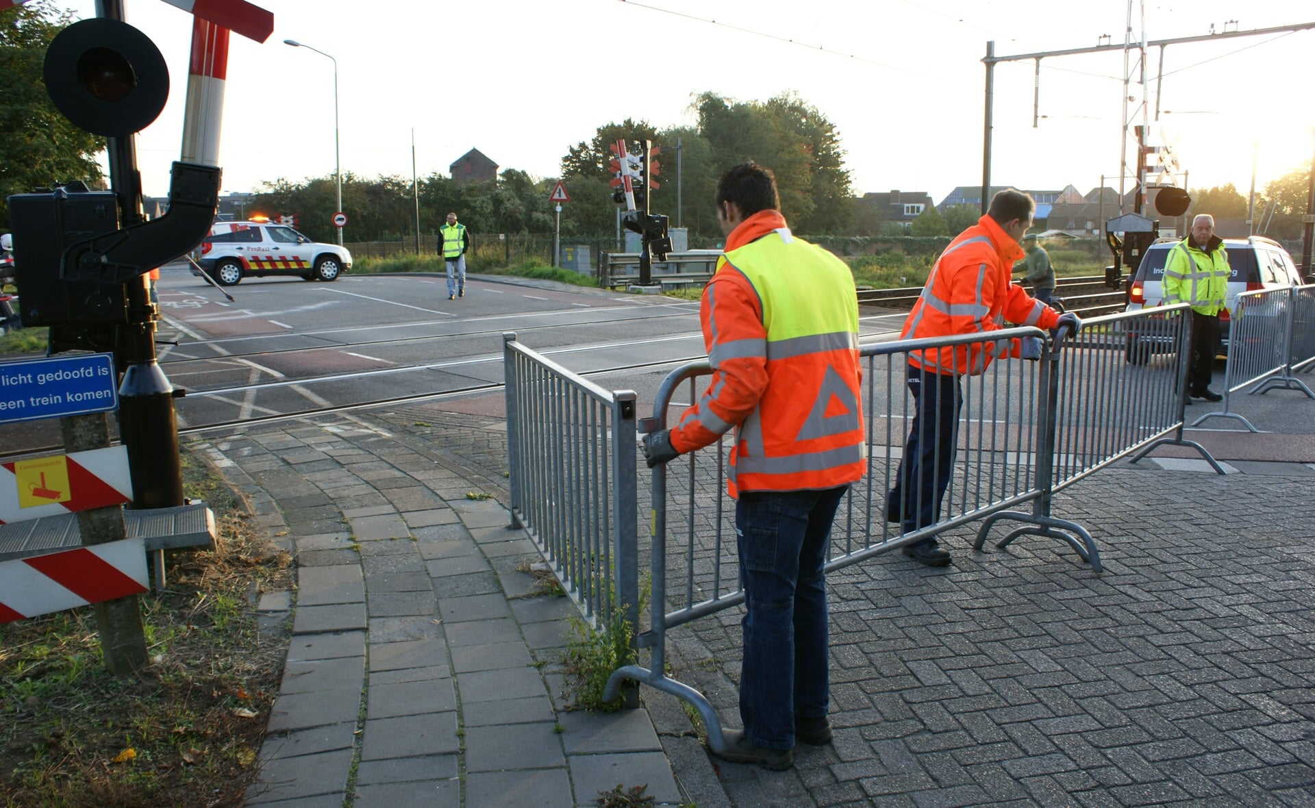 Medewerkers van de gemeente Boxtel zetten de dubbele overweg af met dranghekken. ProRail werkt waarschijnlijk nog de hele dag aan de reparatie van de spoorwegbomen. Een groot deel van de installatie moet vervangen worden. (Foto: Marc Cleutjens).