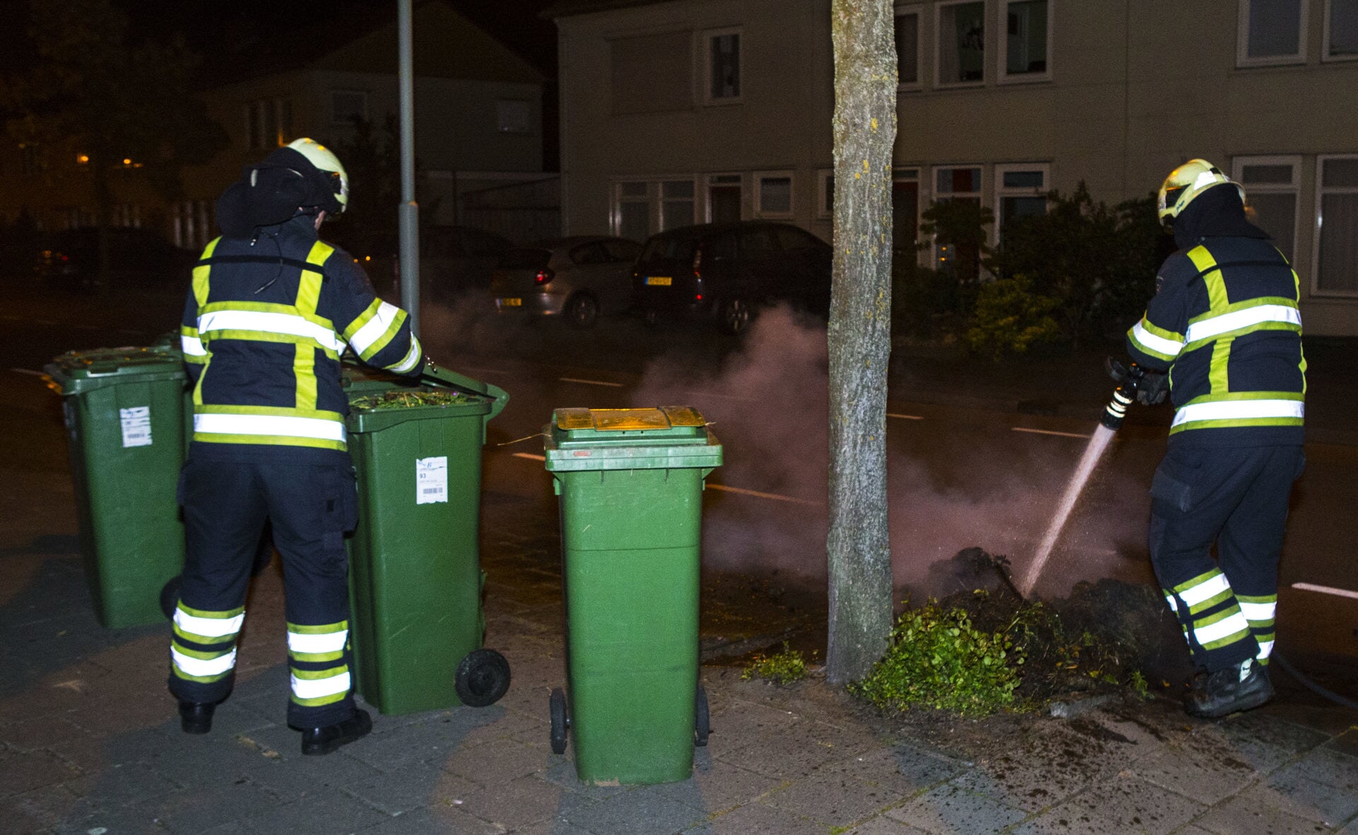 Brandweermannen zijn druk bezig met het blussen van de kliko's aan de Van Hornstraat. (Foto: Sander van Gils).