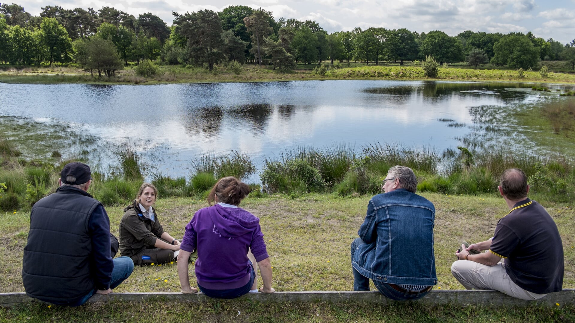 Wandelaars kletsen met elkaar bij een van de vennen in natuurgebied Kampina.