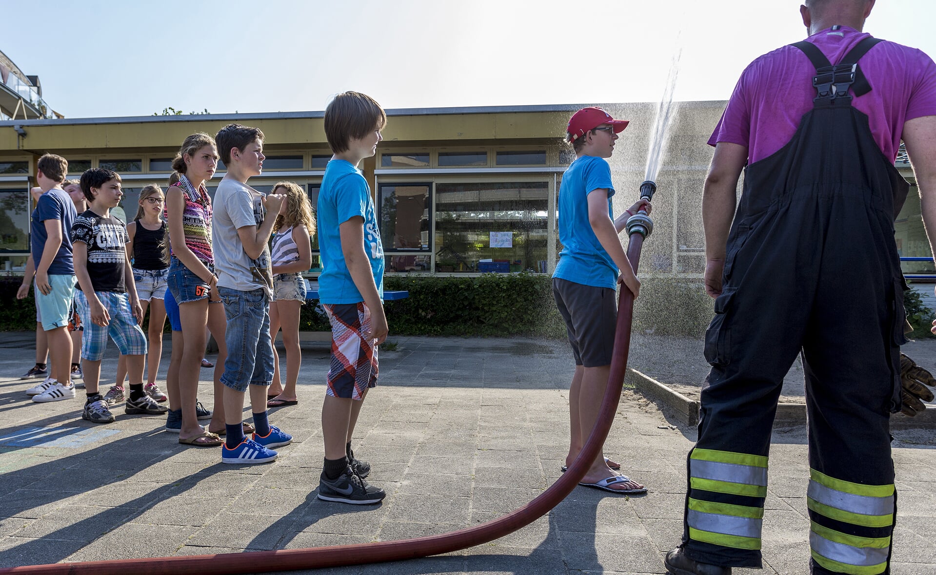 Leerlingen van De Hobbendonken assisteren de brandweer bij het koelen van het dak van hun school. (Foto: Peter de Koning).