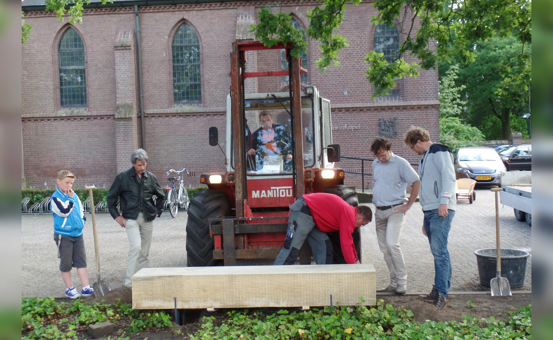 De nieuwe zitbank, die gezaagd is uit het hout van één van de markante oude eiken die zijn verdwenen in het voorjaar, wordt geplaatst in het groenperkje bij de Sint-Lambertuskerk in Gemonde. (Foto: Stefan Latijnhouwers). 