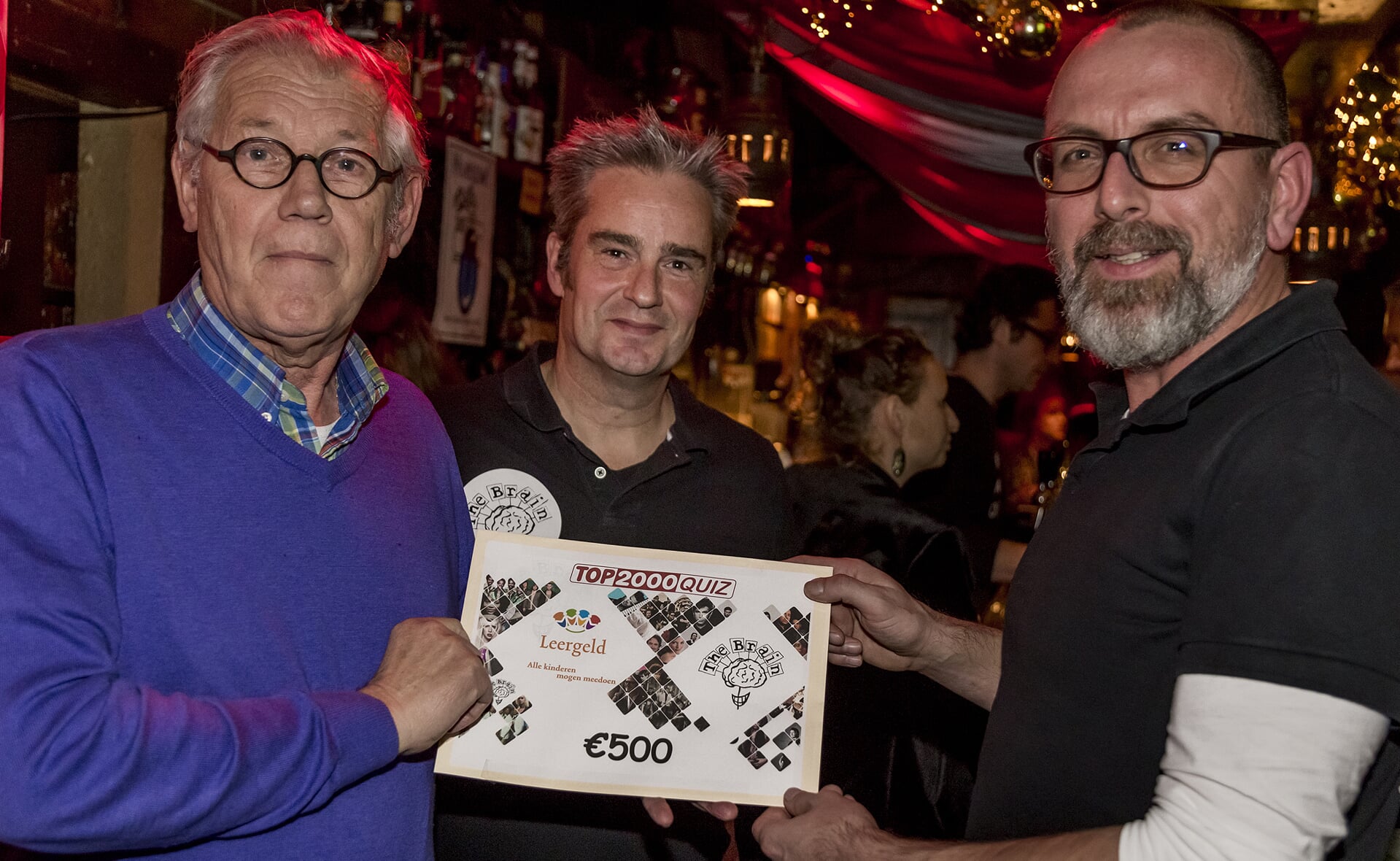Quizmasters Marc de Laat (midden) en Kiske de Leest (rechts) van The Brain overhandigden dinsdag een cheque van 500 euro aan Richard Permentier van stichting Leergeld. (Foto: Peter de Koning).