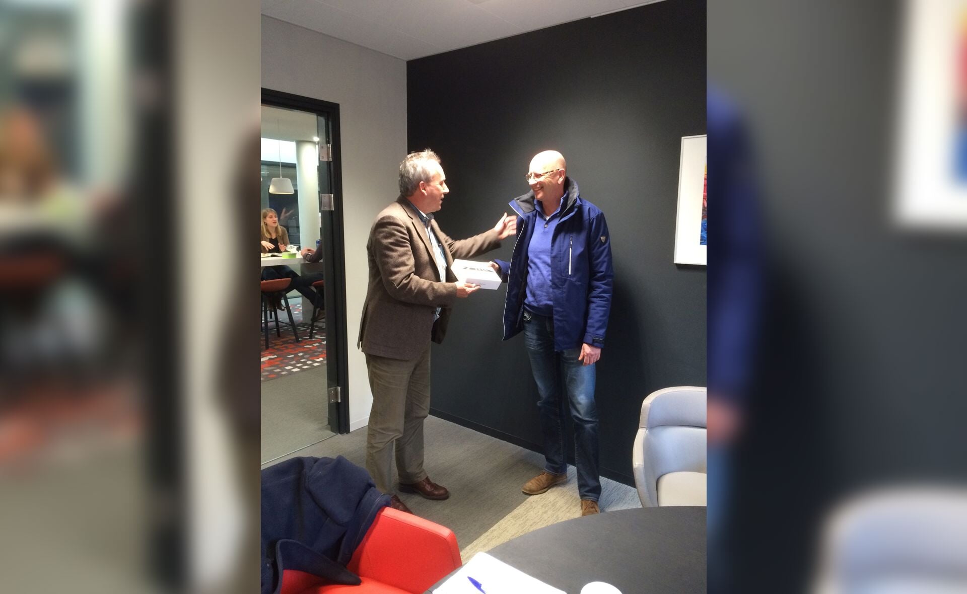 Wethouder Herman van Wanrooij (links) overhandigt de iPad aan Ben Coenen. Hij won de afvalactie.