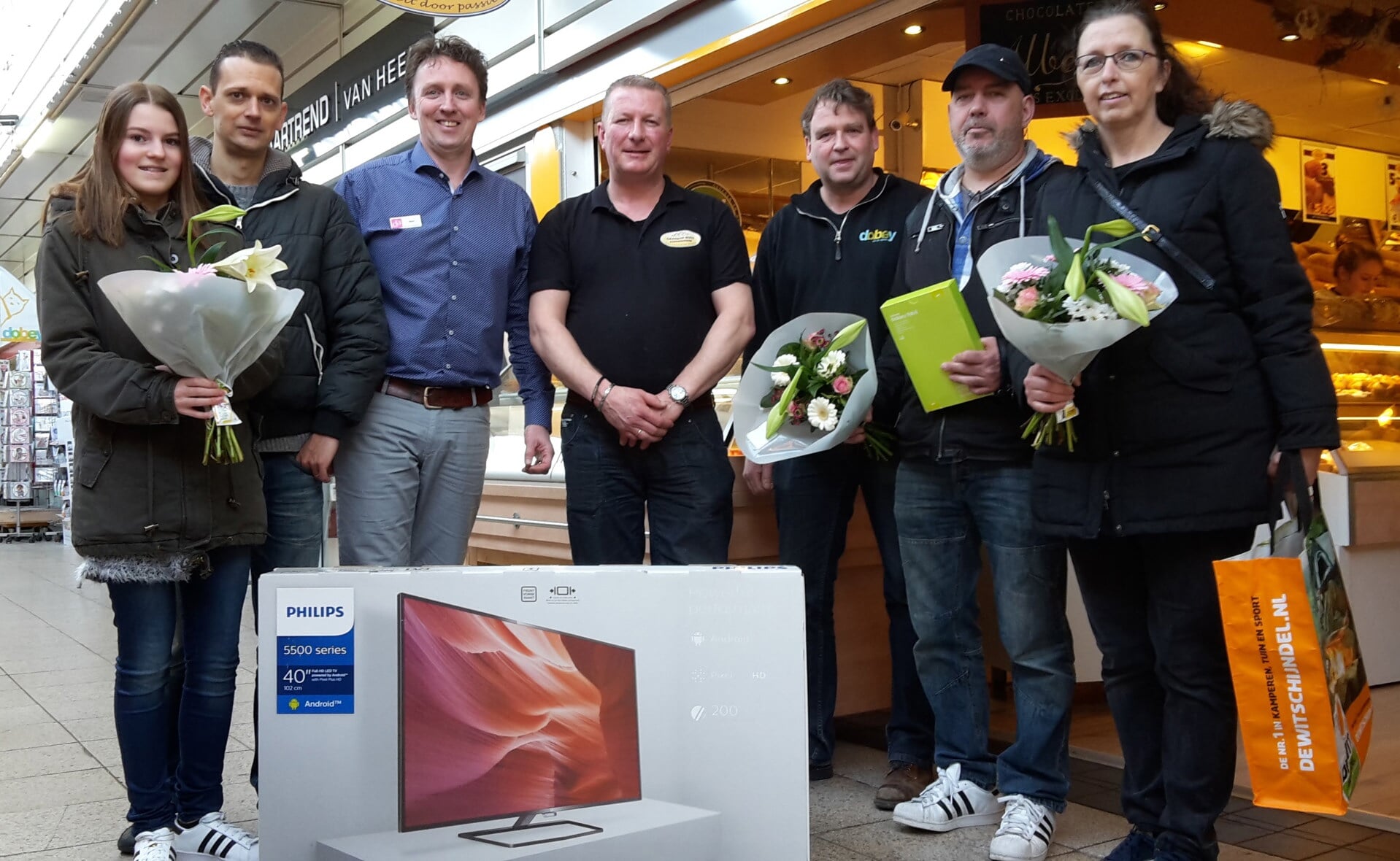 De winnaars van de Prijzenexplosie in maart flankeren drie bestuursleden van winkeliersvereniging Oosterhof. V.l.n.r. Esmée en Renier van den Brandt, Marc van den Biggelaar, Gradjan Buss, Hans van Erp, Henri Becx en Hannie van Wanrooij. (Foto: Henk van Weert). 