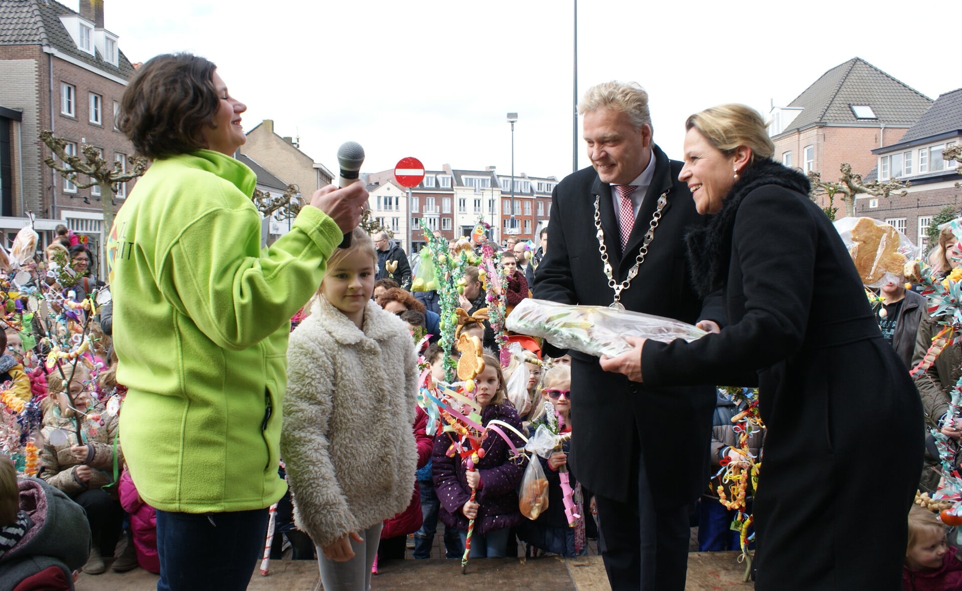 Burgemeester Mark Buijs en echtgenote Christel ontvangen een paasbrood tijdens de ontvangst van de deelnemers aan de Palmpaasoptocht in Boxtel. Links Marion de Koning van Boxtel Vooruit. (Foto: Marc Cleutjens).