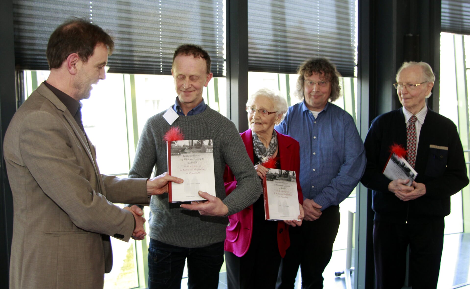 Wethouder Peter van de Wiel (links) reikt de eerste exemplaren van het kartuizerboek uit. Tweede van rechts staat auteur Ger van den Oetelaar. (Foto: Gerard Schalkx).
