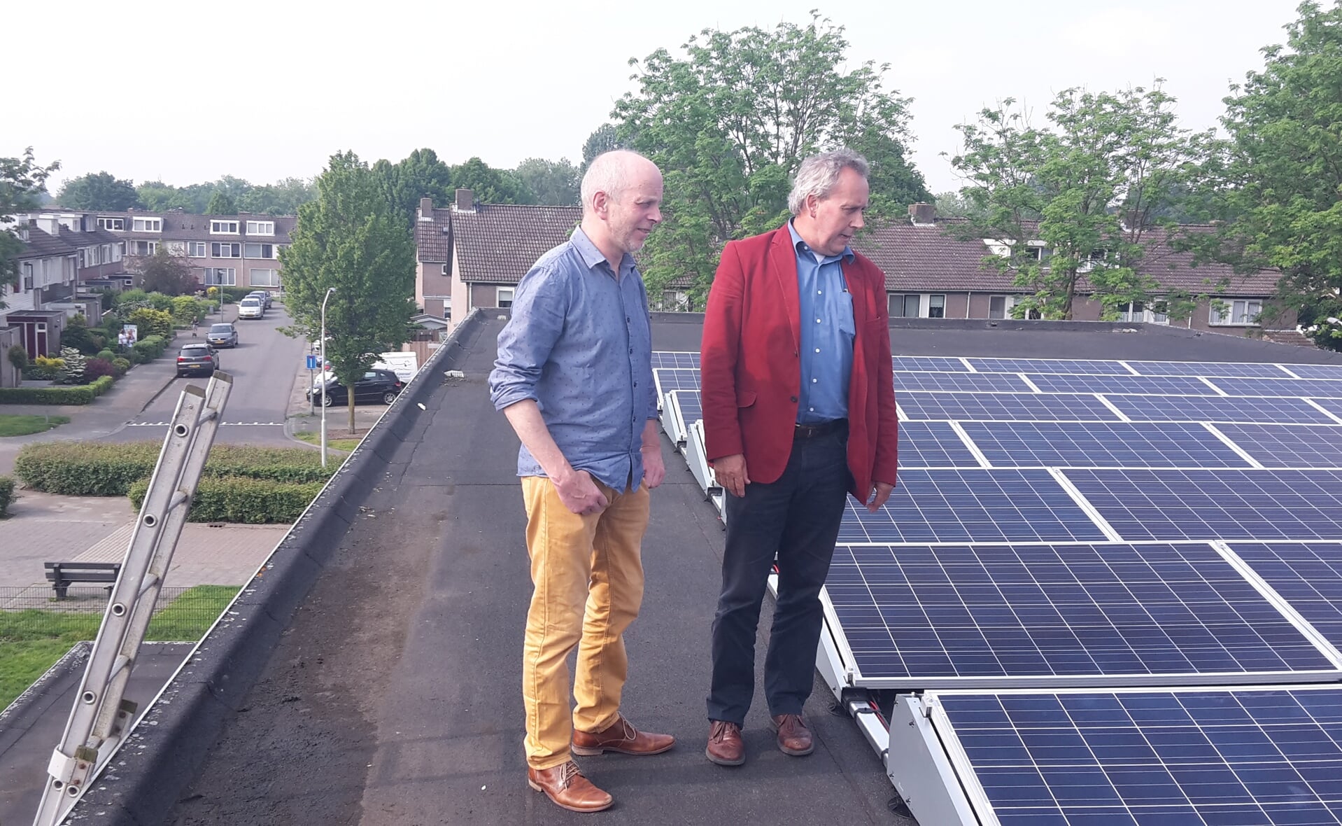 Penningmeester Frank van Bommel van Tabitta en wethouder Herman van Wanrooij bekijken de veertig nieuwe zonnepanelen op het dak van de Boxtelse turnhal. (Foto: Henk van Weert). 