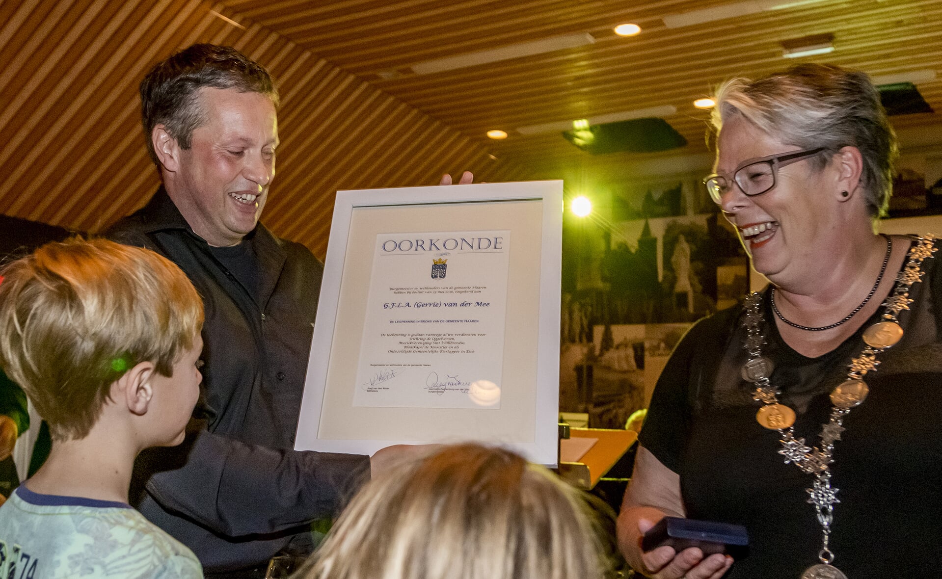 Oud-fanfarevoorzitter Gerrie van der Mee ontving tijdens MaEschtro de bronzen legpenning van verdiensten van de gemeente Haaren uit handen van burgemeester Jeanette Zwijnenburg (rechts).  (Foto: Peter de Koning). 