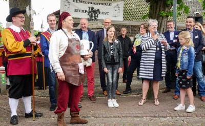 Burgemeester Jeannette Zwijnenburg verwelkomt de nieuwe Esschenaren met warme woorden, terwijl gemeentelijk dorpstapper Gerrie van der Mee klaarstaat met bierpullen. (Foto: Albert Stolwijk).