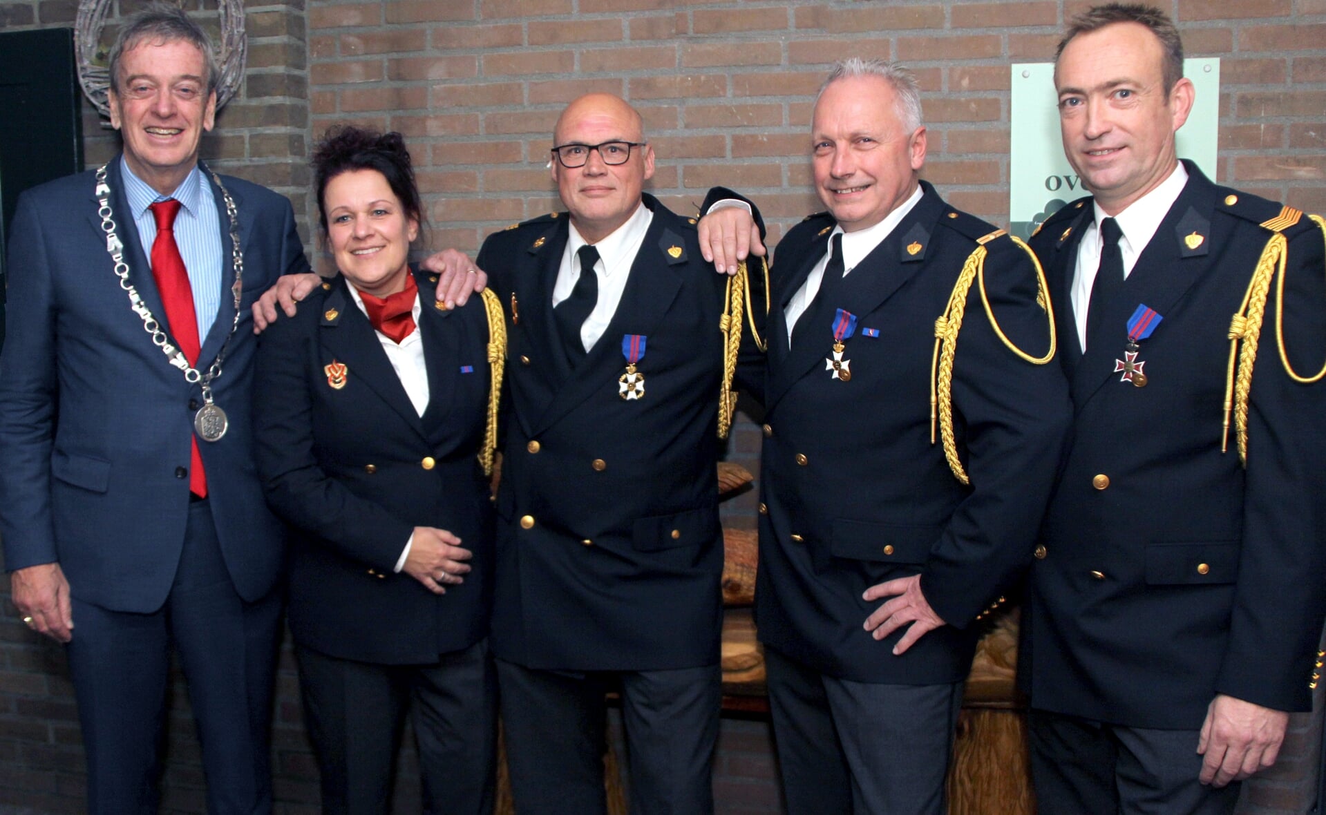 De gedecoreerde brandweermannen Mark Oerlemans, Ad Traa en Frans van Esch (van rechts naar links) poseren met postcommandant Malonka Baijens en burgemeester Fons Naterop. (Foto: Gerard Schalkx). 