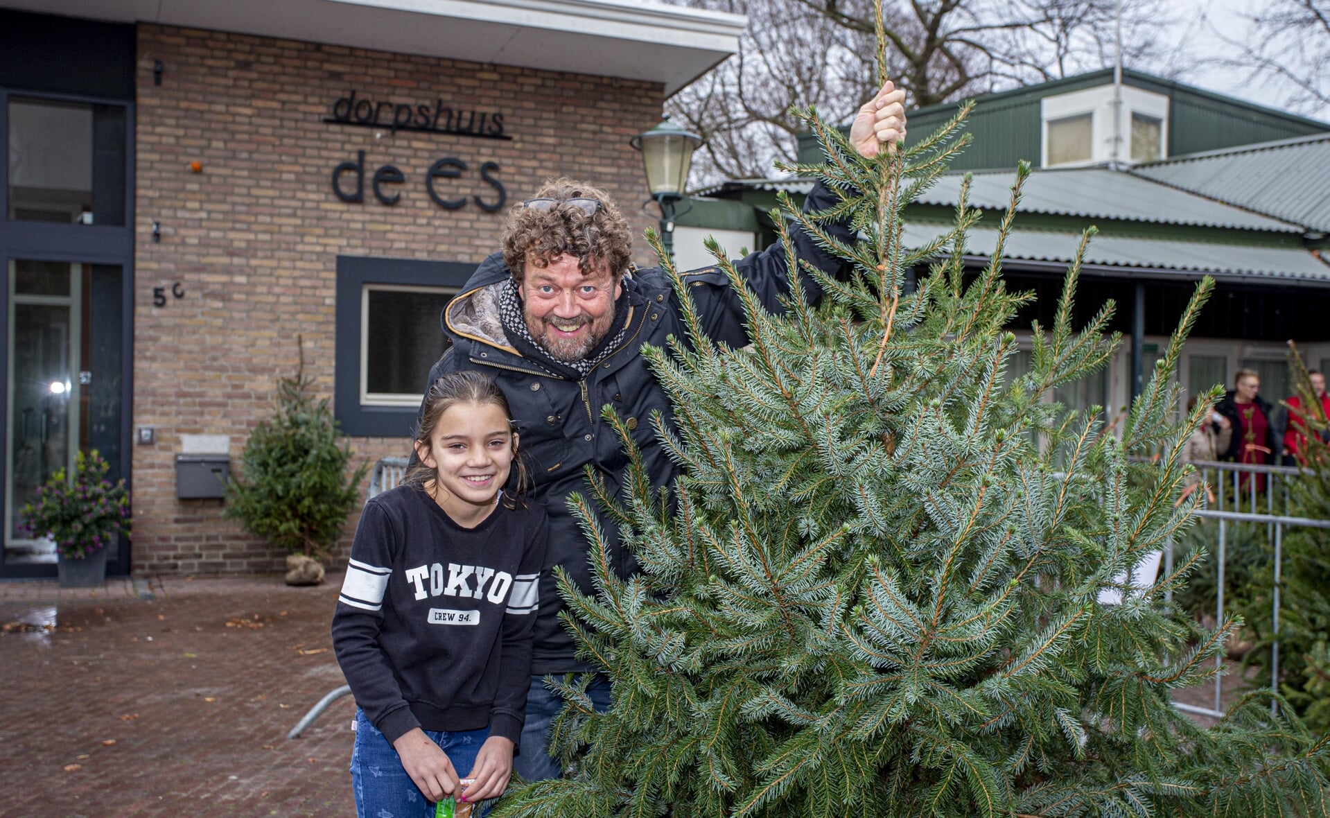 Twee jaar geleden scoorden Harold de Bie en zijn dochter Katie een kerstboom bij de fanfare. Deze keer is de verkoop niet bij dorpshuis De Es zoals hierboven, maar aan de Postelstraat 21.