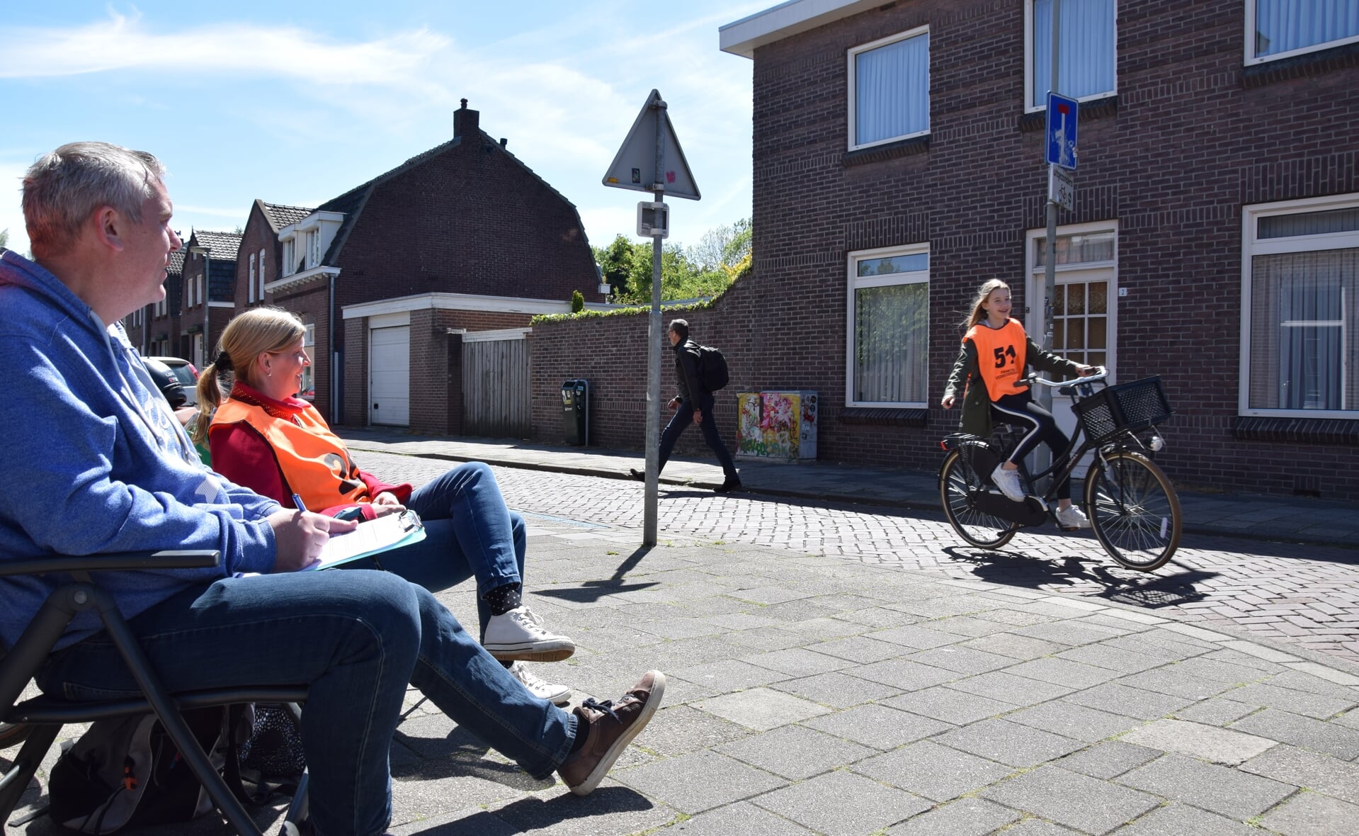 Remon van der Ven en Jessica Spitters genieten niet alleen van de netjes fietsende scholieren, maar ook van het warme zonnetje. (Foto: Rens van den Elsen).