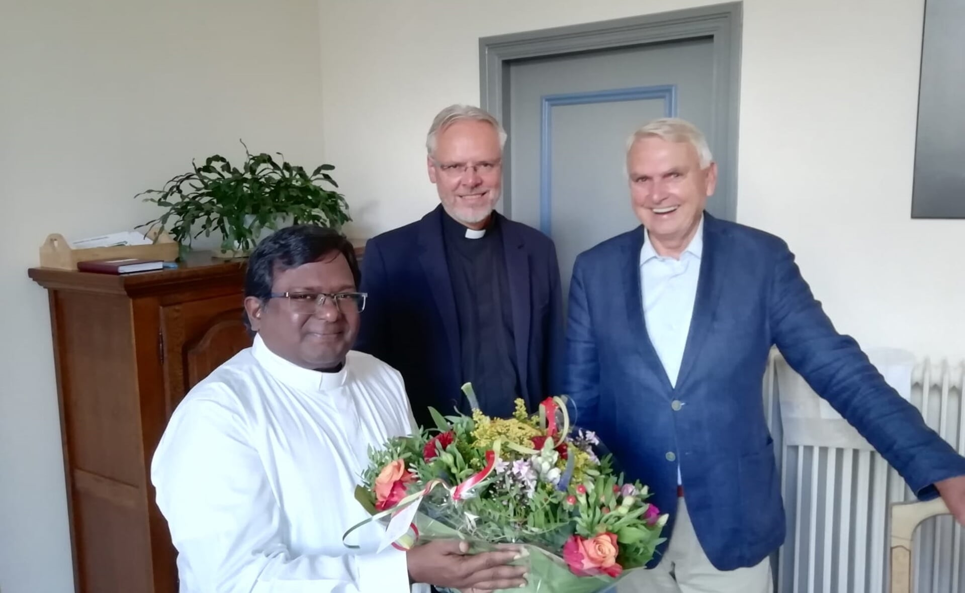 Marshal Stanislas (links) kreeg gisteren een warm welkom van pastoor Geertjan van Rossem (midden) en Jos Polman van de Heilig Hartparochie.