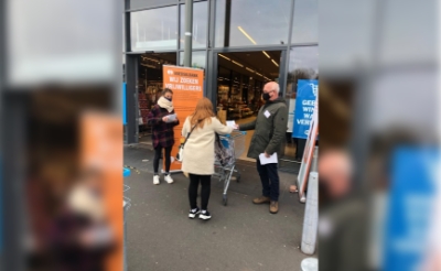 <p>Vrijwilligers van de Voedselbank flyeren bij de deur van supermarkt Albert Heijn. Ze vroegen klanten om extra spullen te kopen. (Foto: eigen collectie). </p>