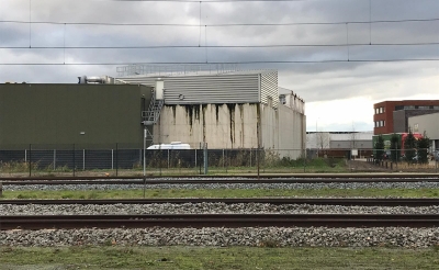De natte plekken aan de buitenkant van het waterzuiveringsbassin van HydroBusinnes zijn duidelijk zichtbaar. De foto is genomen vanaf de Parallelweg Zuid, aan de overkant van het spoor. (Foto: PvdA-GroenLinks).