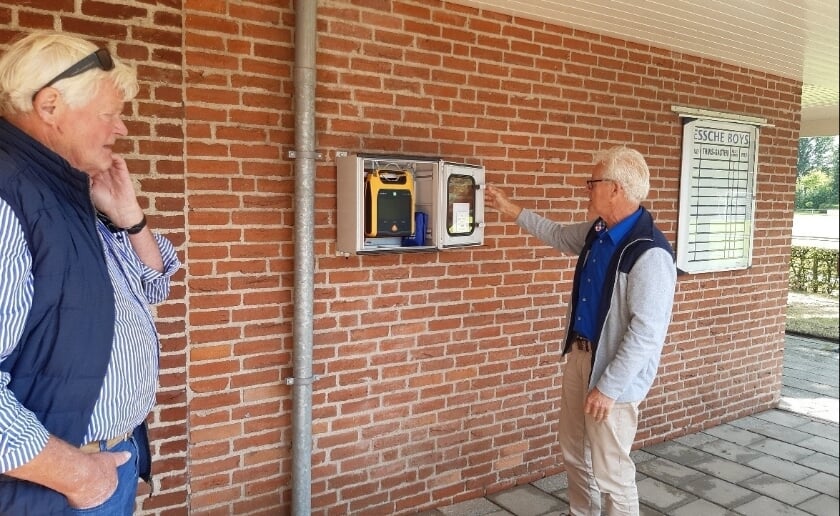 Twee leden van de werkgroep Heartsafe Esch bij de AED op het sportpark in het dorp. Die hangt nu op een plek waar iedereen erbij kan, zonder sleutel of pasje. (Foto: Heartsafe Esch).