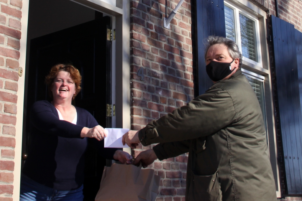 <p>Jos Sanders, uitbater van café 't Groene Woud, overhandigt het borrelpakket voor de Ouwe Koeien Carnavalszitting van OLG aan voorzitter Reggie van Genuchten van prinsenvereniging De Ploegers. </p>