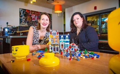Legomaster Lola Nouwens (links) en jongerenwerker Sháron Willems slaan de handen ineen. Het duo gaat 24 jongeren begeleiden terwijl die hun fantasie met de bouwsteentjes de vrije loop laten. (Foto: Bas van den Biggelaar).