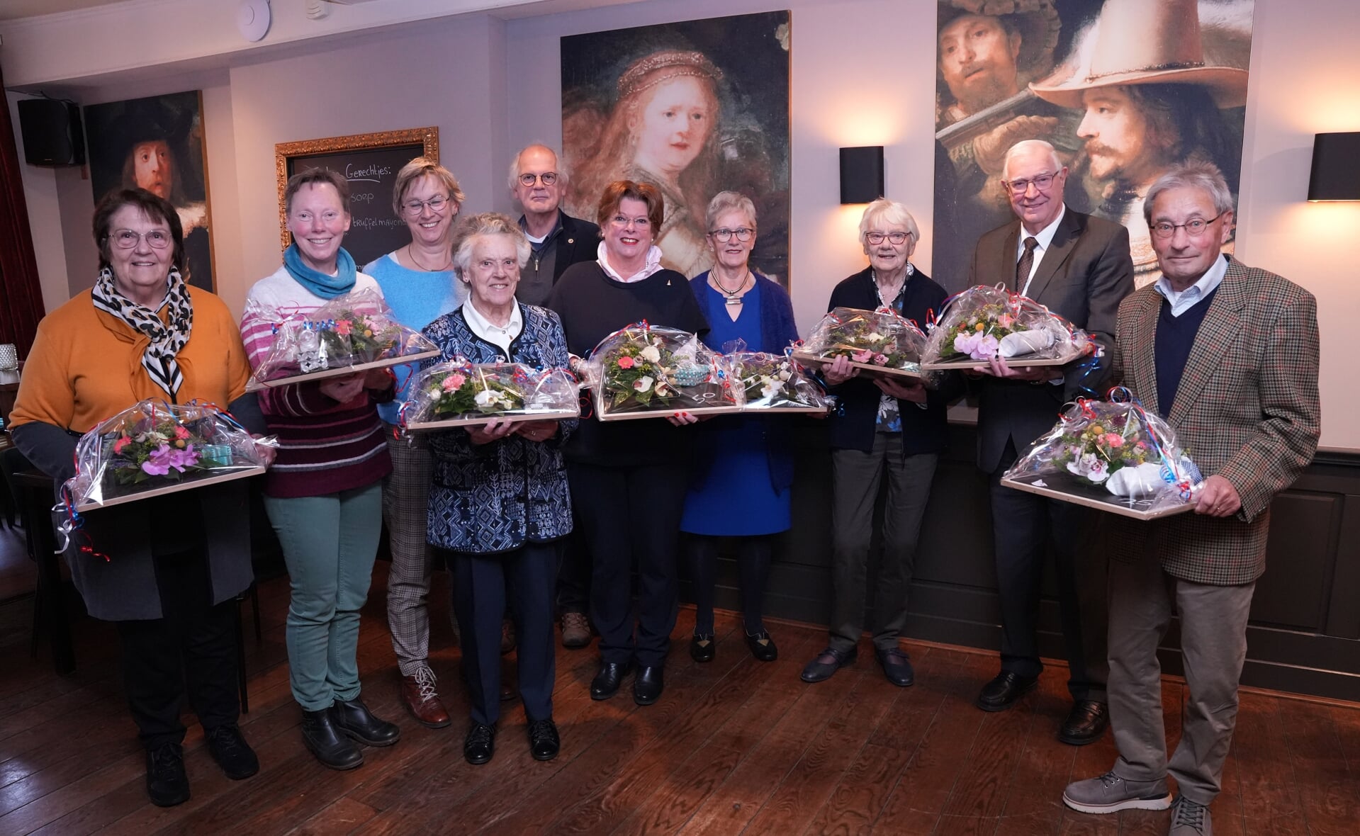 De acht jubilarissen van het Sint-Petruskoor, met twee dochters van Betsie van Kessel, die postuum werd geëerd. De zangers hebben menig viering opgeluisterd.