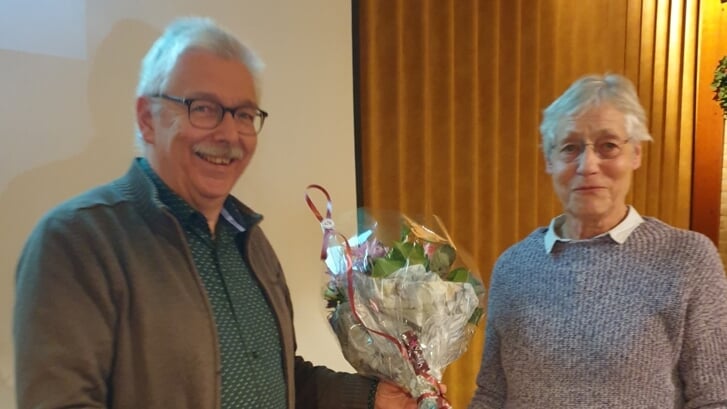 Hans van der Schoot overhandigt het eerste exemplaar van het jaarboek 2021 samen met een boeket bloemen aan Thea Tilburgs.