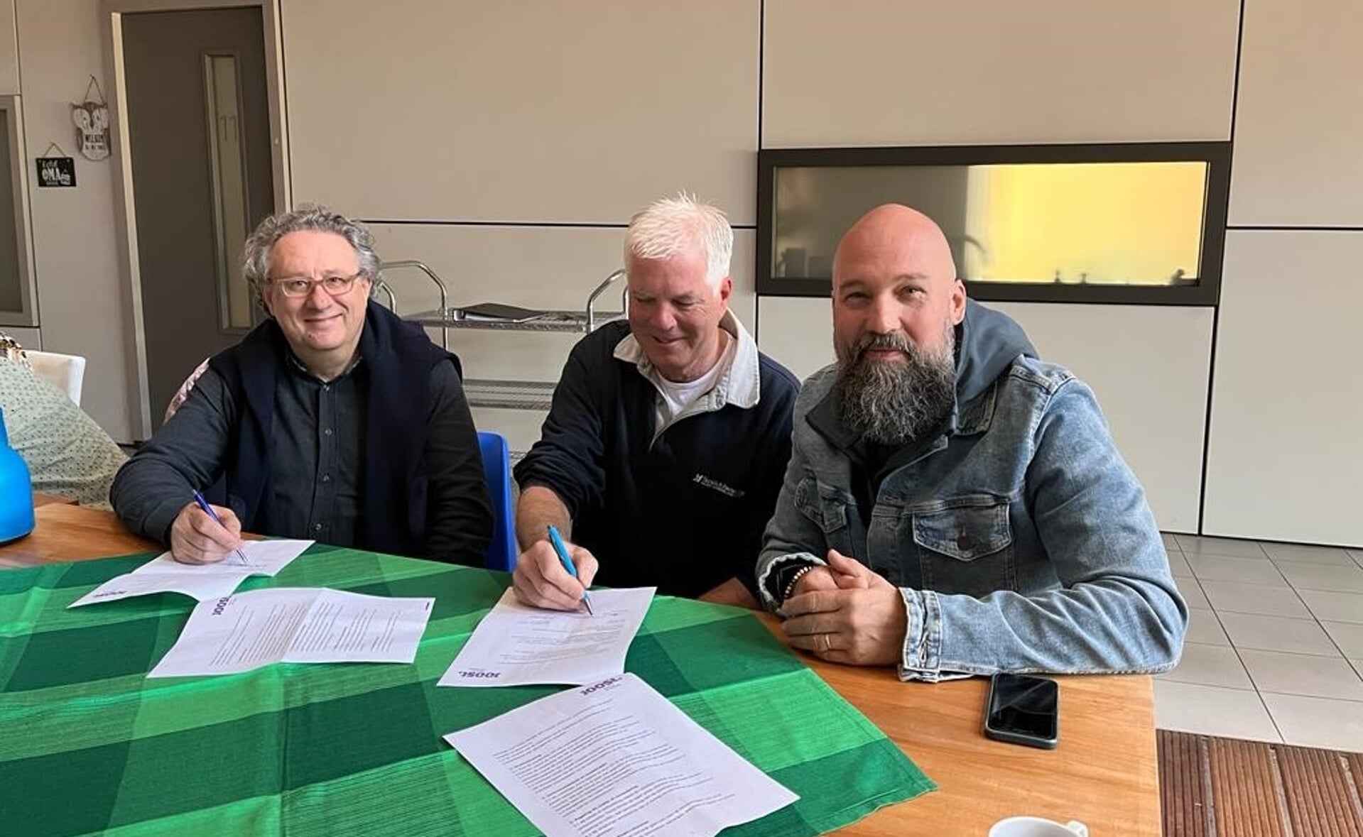 Matthias Rauterberg (links) en Marc Hoyng (midden) tekenen het vrijwilligerscontract met een vertegenwoordiger van woonstichting Joost.