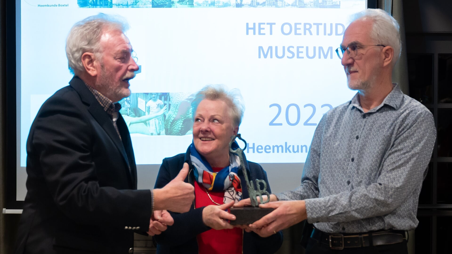Heemkundevoorzitter Henk van Beers (links) reikte wisseltrofee aan directeur René Fraaije van het Oertijdmuseum Boxtel. In het midden echtgenote Thea Fraaije-van Boom. 