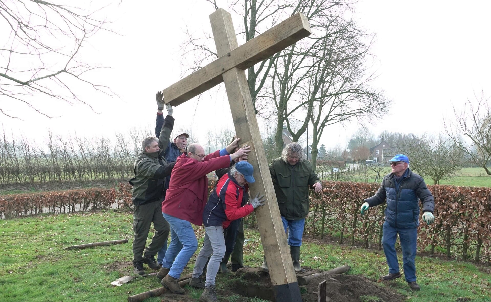 Vrijwilligers van erfgoedvereniging Kèk Liemt zijn druk in de weer met het kruis aan de Pastoor Dobeleijnstraat weer op zijn plek te hijsen. 
