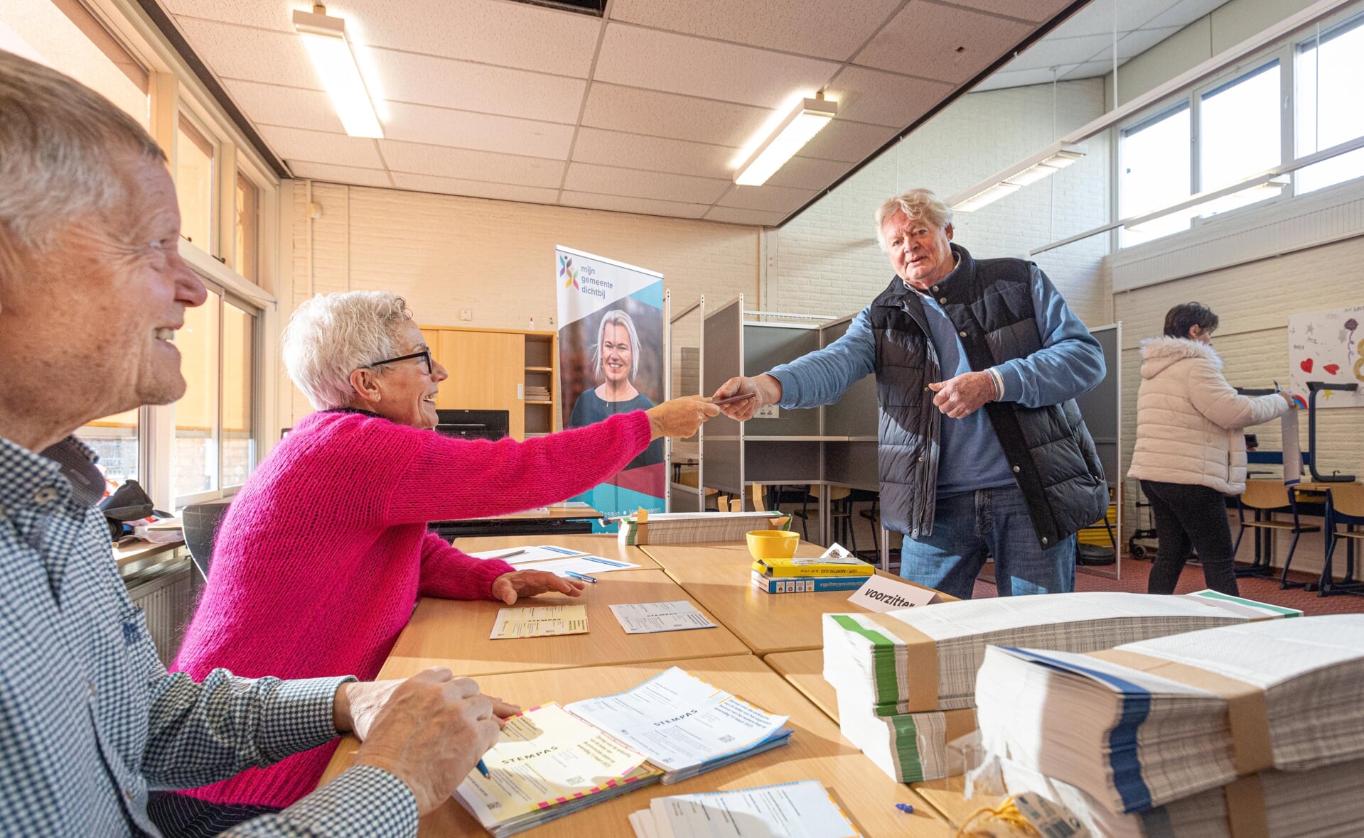 Edwin Leijten (links) en Leida Nouwens hebben de identiteit van deze kiezer gecontroleerd. De Esschenaar wist het stembureau wel te vinden, ondanks de nieuwe locatie: de school in plaats van De Es.