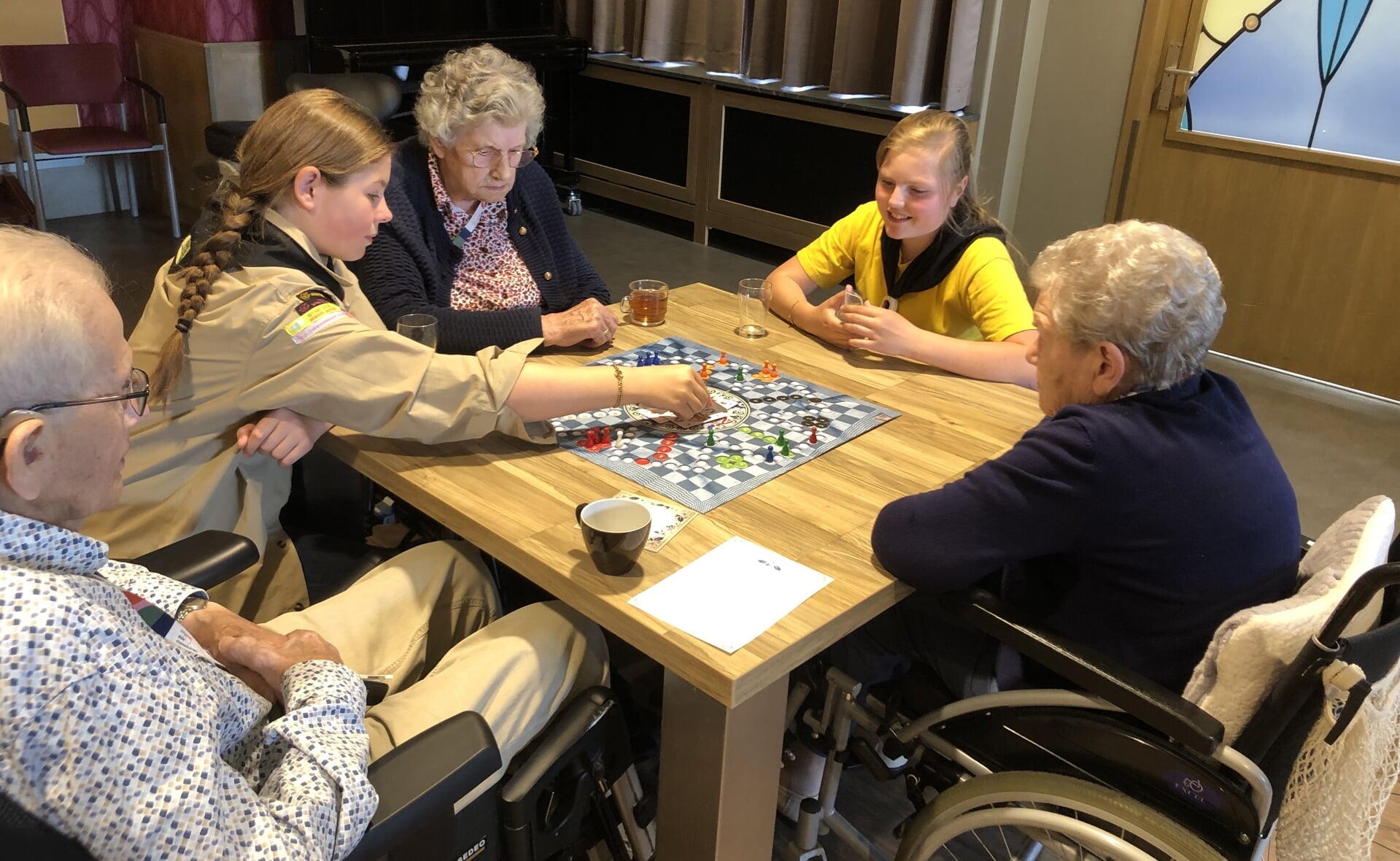 Gidsen van Scouting Boxtel spelen gezelschapsspelletjes met bewoners van verpleeghuis Liduina.