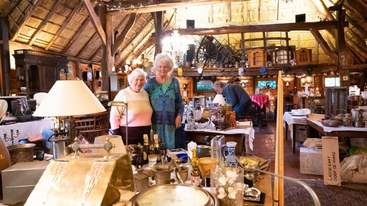 Rinie Plantema (links) en Cis Vissers, voormalig ambassadeur van stichting KiKa, in de dwarsdeelschuur vol spullen voor de verkoop tijdens een eerdere editie van de garagesale.
