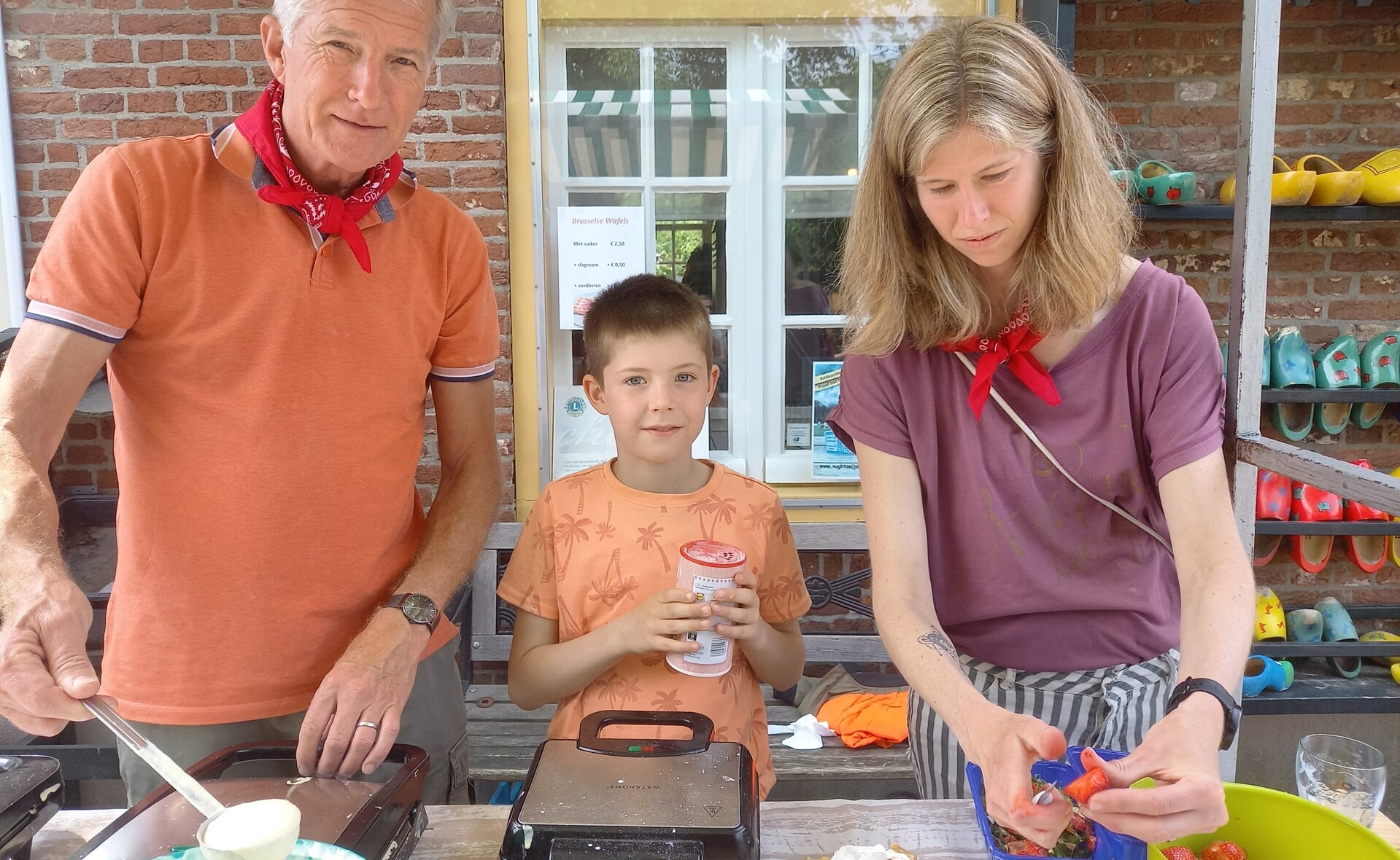 Opa René Huijbers, Niels de Hond en zijn moeder Marjolein zijn wafels aan het bakken en verkopen.