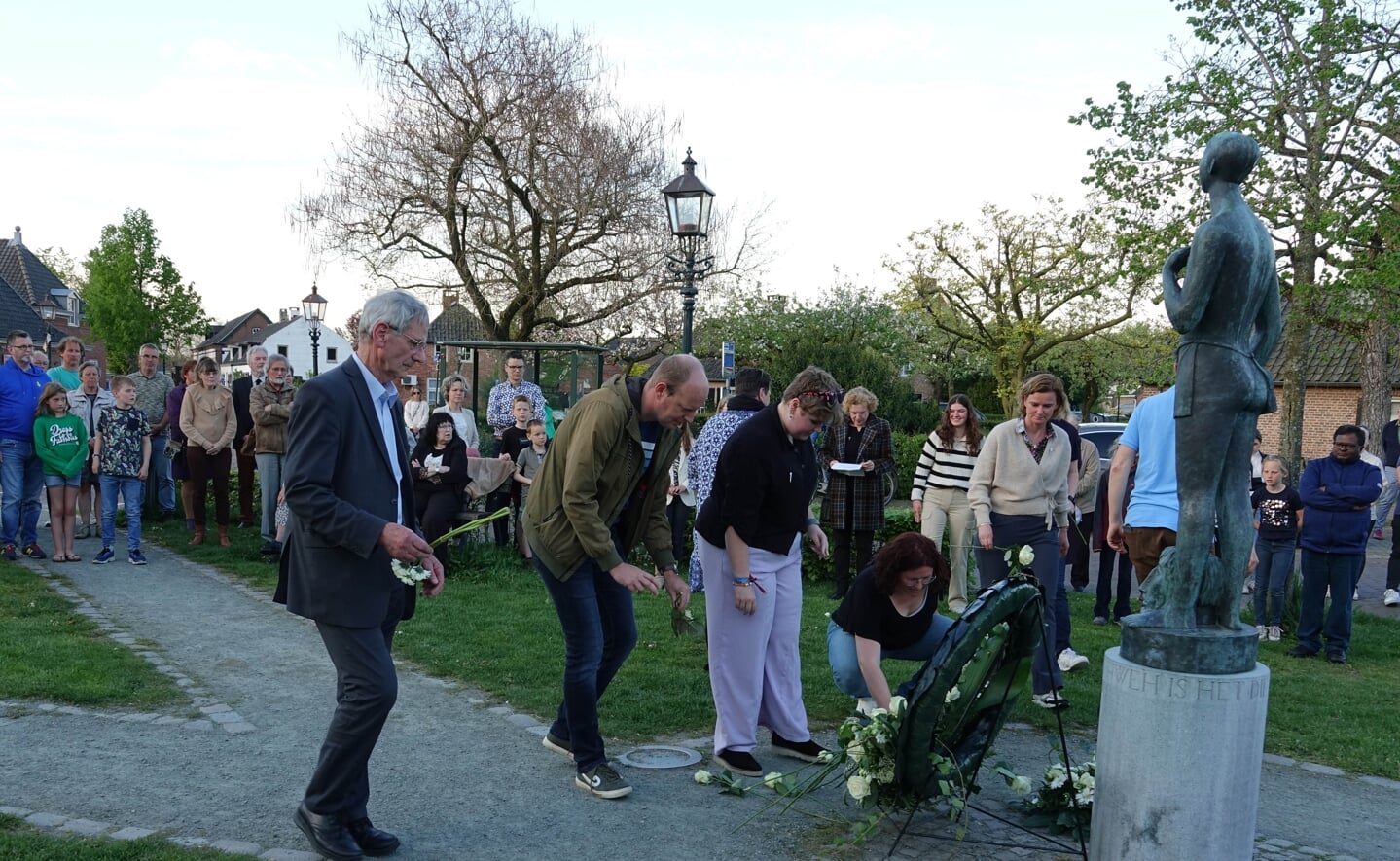 Deelnemers aan dodenherdenking in Liempde leggen bloemen bij het beeld van David en Goliath in het Concordiapark.