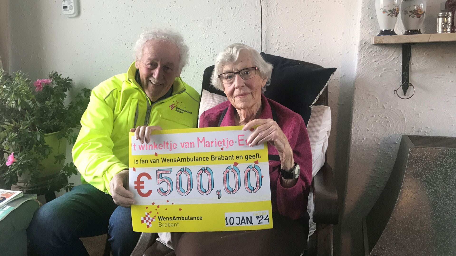 Vrijwilliger Barry van Brakel van WensAmbulance Brabant neemt uit handen van Marietje van Eijndhoven een cheque in ontvangst.