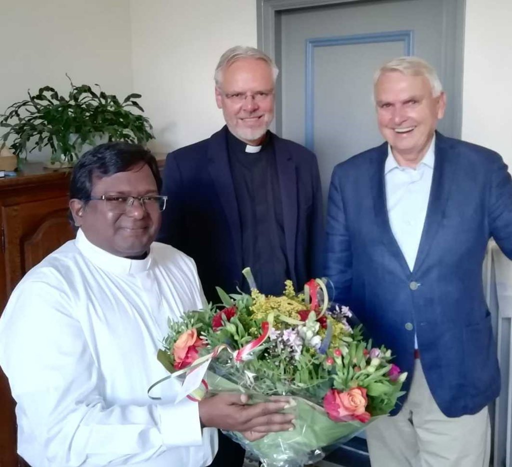 Kapelaan Marshal Stanislas uit India werd verwelkomd met bloemen door onder meer pastoor Geertjan van Rossem (midden) en vicevoorzitter Jos Polmann. (Foto: Heilig Hartparochie). 