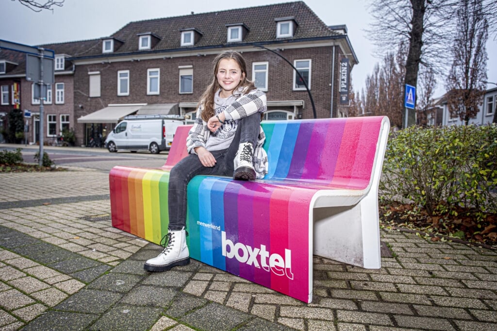 Tess op het regenboogbankje dat ze zelf ontworpen heeft. (Foto: Bas van den Biggelaar).