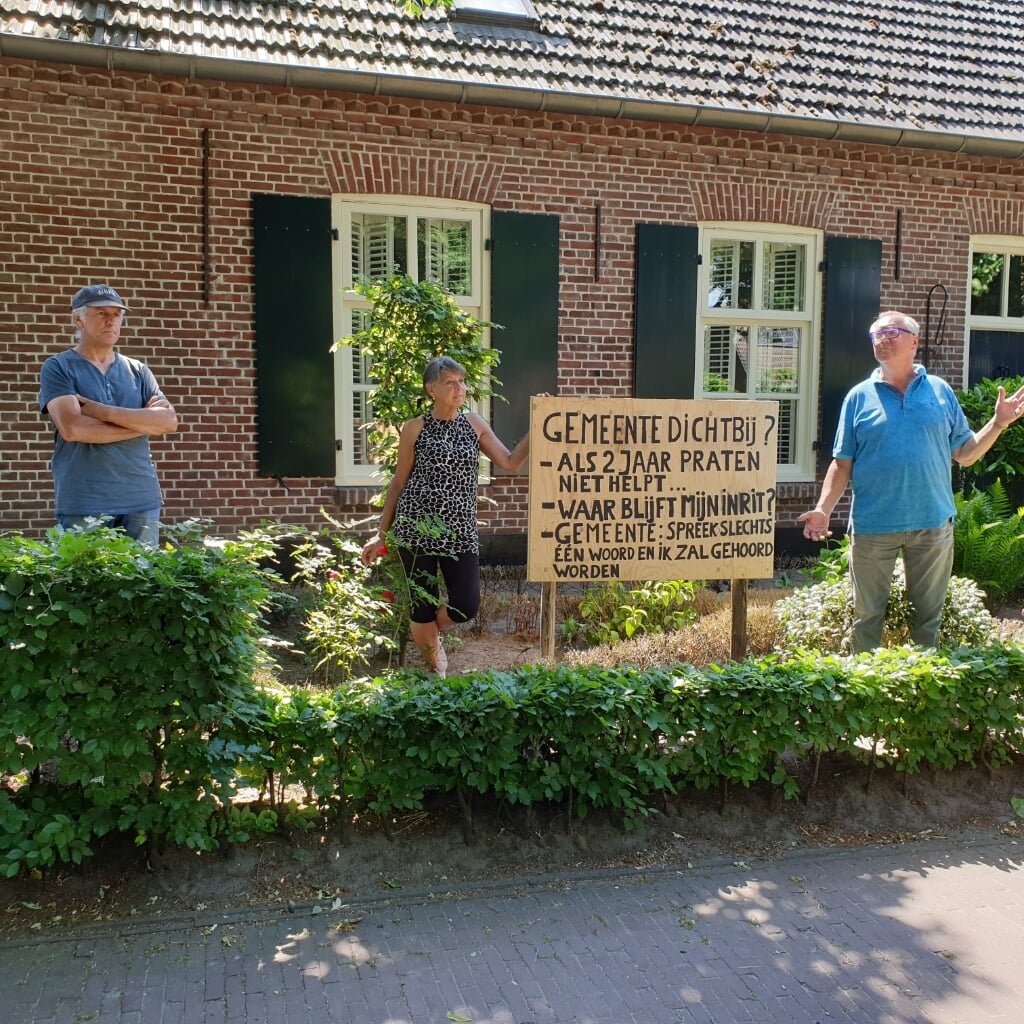 Met een protestbord in de tuin vroegen Carla van Wijk en haar buurmannen Ton van Boxtel (rechts) en Marcel Saris aandacht voor hun probleem: een aansluitende uitrit van de achtertuin op het nieuwbouwproject Kerkweide West. (Foto: Ellie van Meurs). 