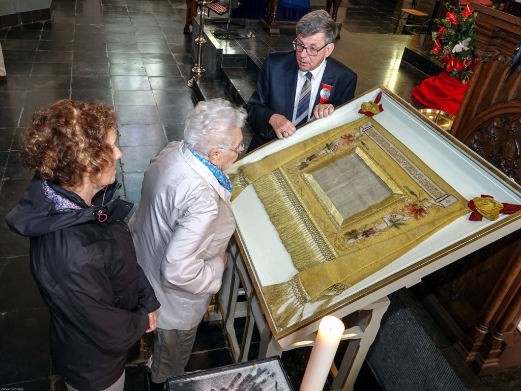 Bezoekers bekijken de relikwie in de Sint-Petrusbasiliek. Daar kregen zij ook uitleg kregen over het Boxtelse mirakel door bestuursleden van de Heilig Bloedstichting, zoals penningmeester Frans van Susante (rechts). (Foto: Albert Stolwijk).
