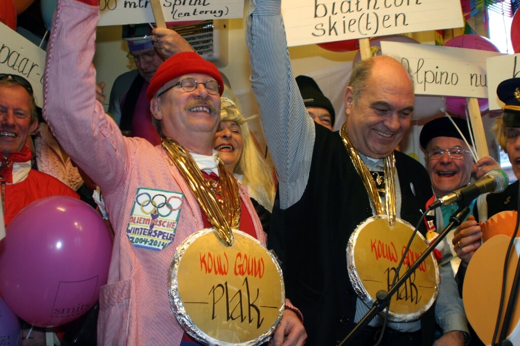 Gerard Schalkx (links) en wijlen Jan van der Linden ontvangen van 't Herriemenieke tijdens de Oliempische Spelen een bevroren taartbodem als Kouw Gouw Plak op de jaarlijkse Kolderzitting in café 't Wapen van Liempde. (Foto: 2004). 