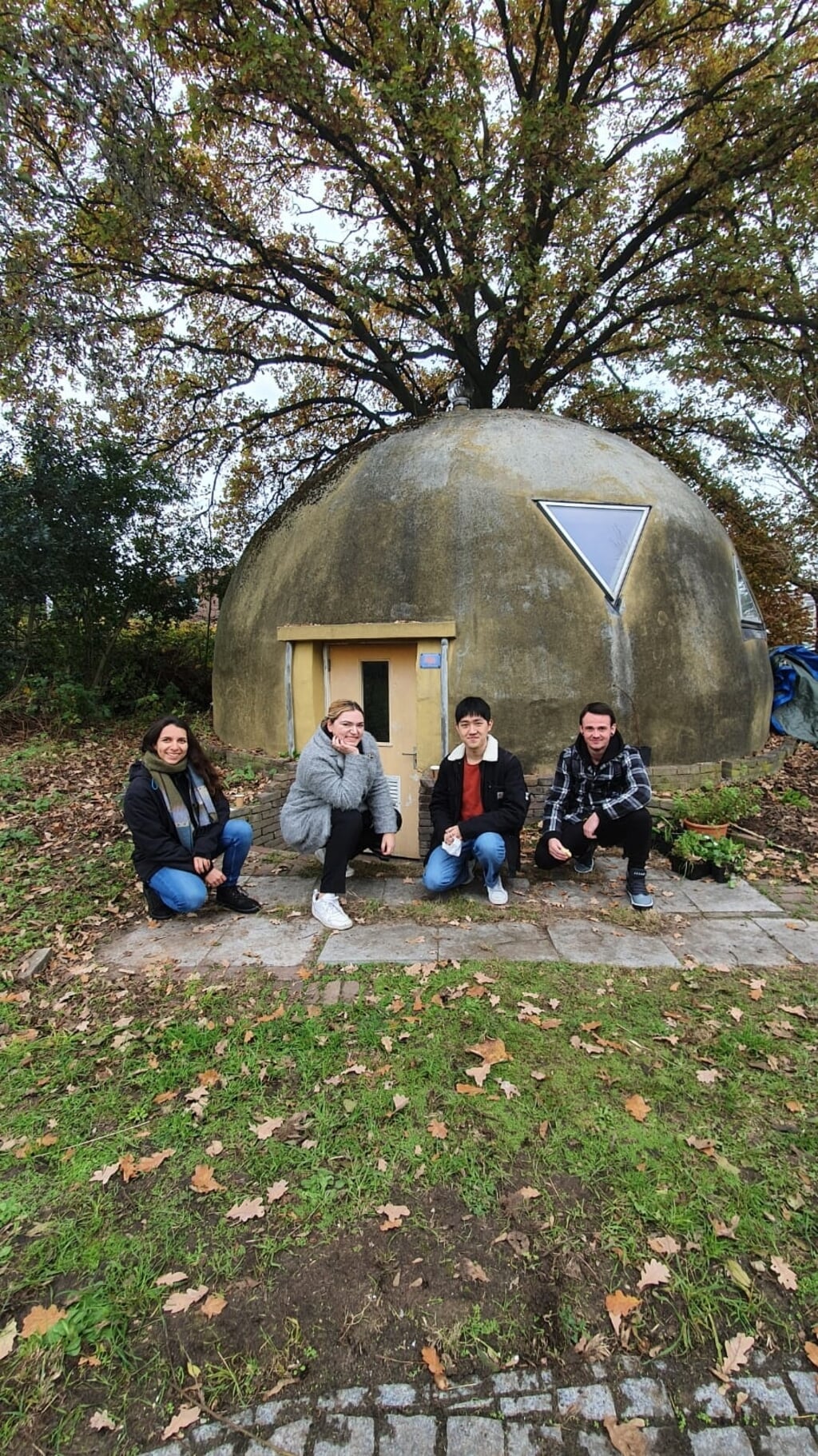 Kamelia, Simona, Yuming en Seanan (van links naar rechts) poseren voor de bolwoning van De Kleine Aarde. De vier studenten hebben tijdens een onderzoek alle toekomstige functies van het kringloophuis in kaart gebracht. (Foto: Katja Staring)