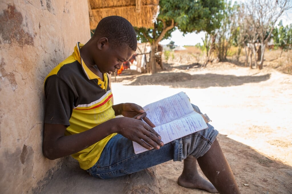 Dennis maakt huiswerk. Hij is een van de Zambiaanse jongeren die wordt geholpen tijdens het Vastenactieproject van de Heilig Hartparochie in de gemeente Boxtel.