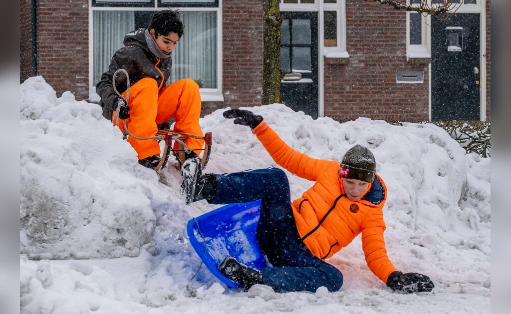 De vrienden Sil (links) en Siem sleeën van een zelfgemaakte sneeuwhelling af in de Prins Hendrikstraat. En dat is toch moeilijker dan het lijkt... (Foto: Peter de Koning).
