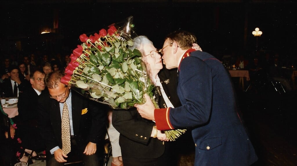 Harmonievoorzitter Willy van de Loo overhandigt vijftig rode rozen aan Gerdien van Geel, echtgenote van de grondlegger van de Van Geel Groep. 