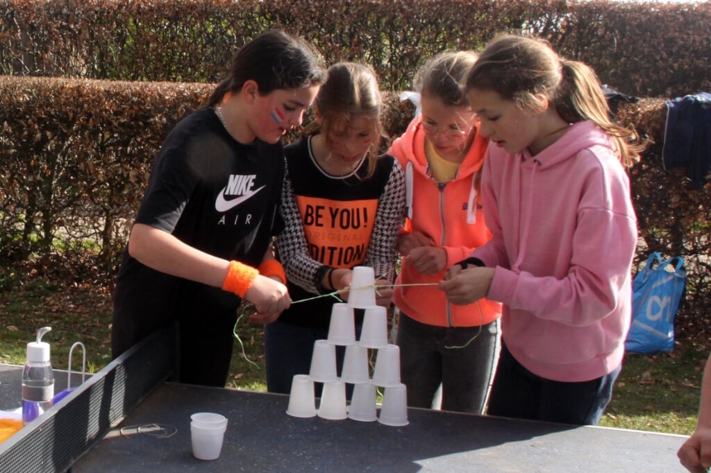 Leerlingen van De Oversteek bouwen met behulp van een touwtje een piramide van plastic bekertjes. (Foto: Gerard Schalkx).
