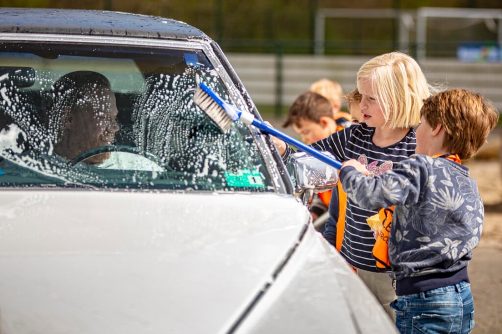 Bezoekers van Klein Kindercentra poetsen auto's van bezoekers. (Foto: Bas van den Biggelaar).