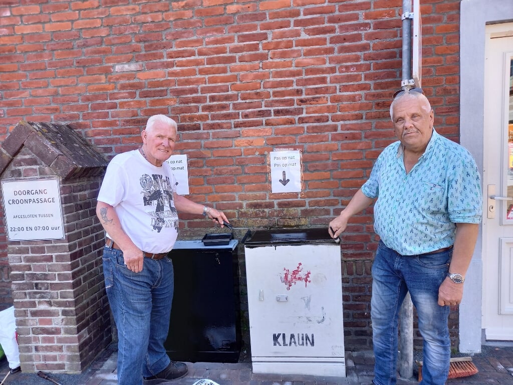 Ben Heylen (links) en Marie Fick schilderen twee elektriciteitskastjes bij telefoniewinkel Ring & Go netjes zwart. (Foto: Jan Hermens).