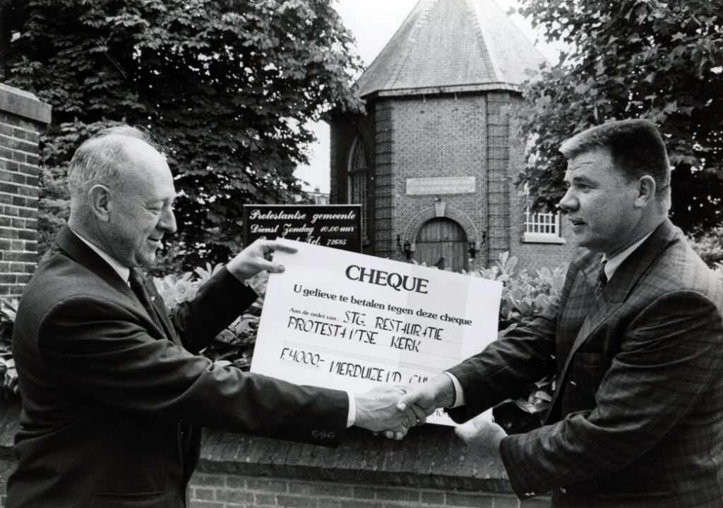 Evert van Gelder (links), voorzitter van het restauratiecomité van de protestantse kerk, ontvangt een cheque uit handen van Martien Tielen van de plaatselijke Rabobank. 