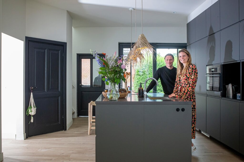 Gerard van Beurden en Joyce Scheeren in hun moderne keuken. Links een van de zwartgelakte paneeldeuren die nog origineel zijn. 
