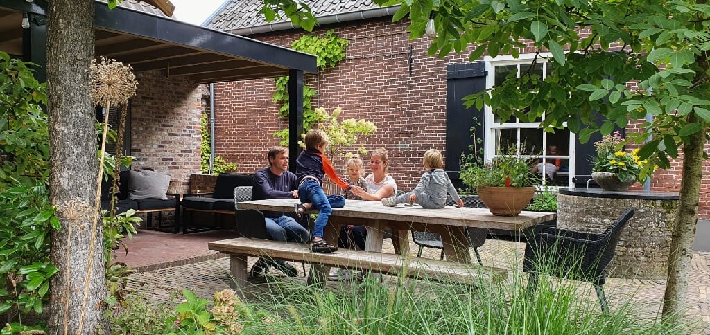 Pieter, Marleen en hun kinderen Tijn, Suze en Thomas genieten volop in de tuin achter hun monumentale woonboerderij. 